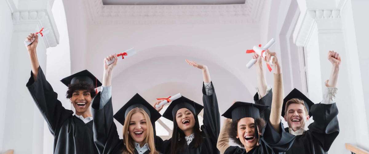 Excited multicultural students with diplomas showing yes gesture